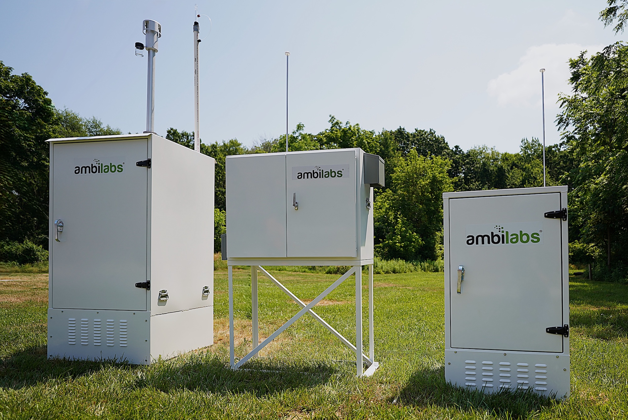 Three Ambilabs branded outdoor monitoring enclosures on grass