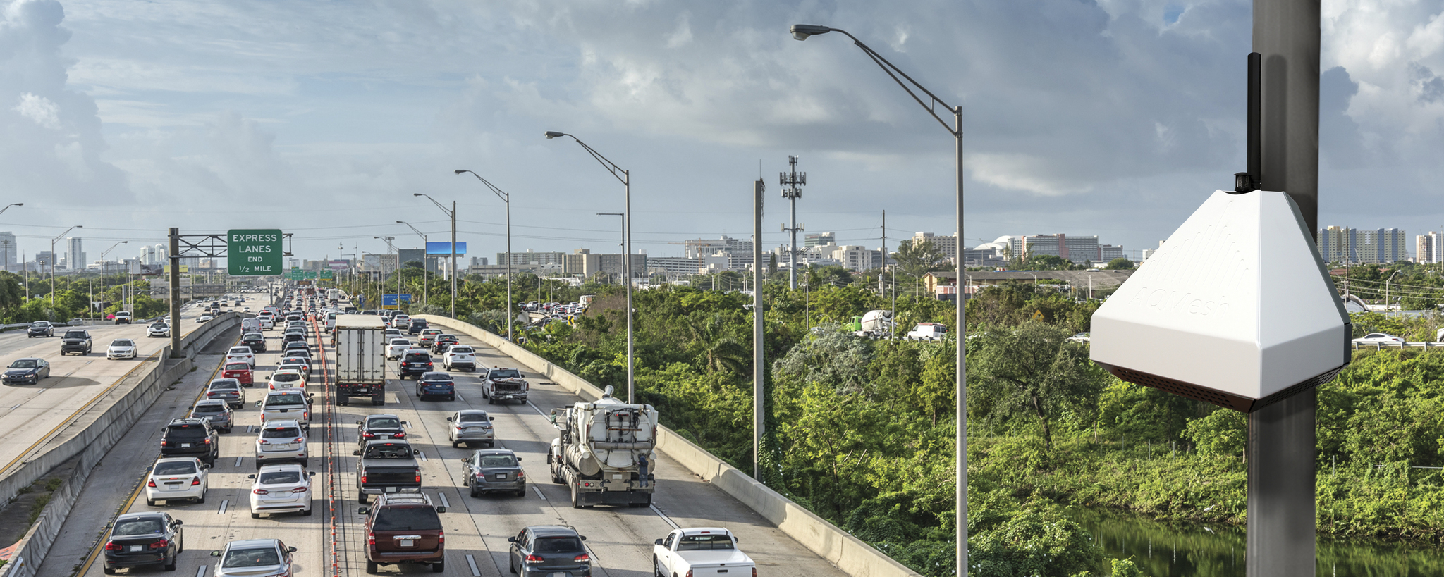 AQMesh air quality sensor pod mounted on a pole above highway traffic